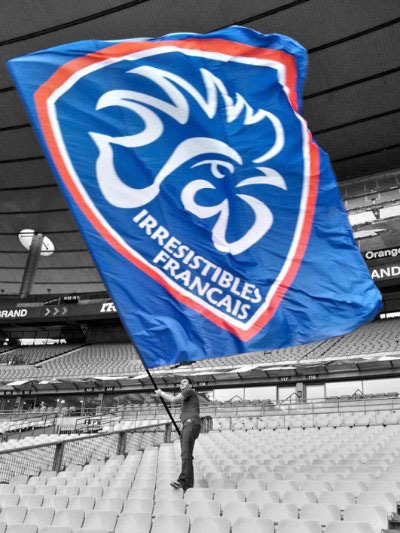 Un supporter agite le grand drapeau des Irrésistibles Français dans les tribunes vides d'un stade